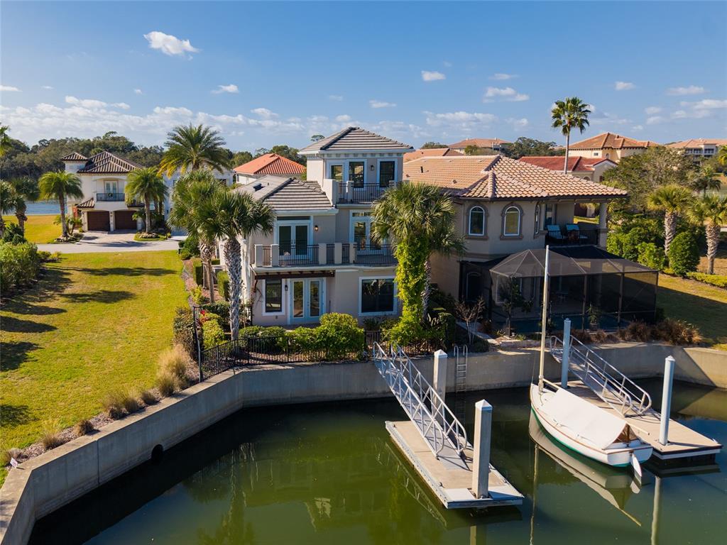 An aerial view of a multi-story waterfront home with a private dock and boat — 259 YACHT HARBOR DRIVE, PALM COAST, FL