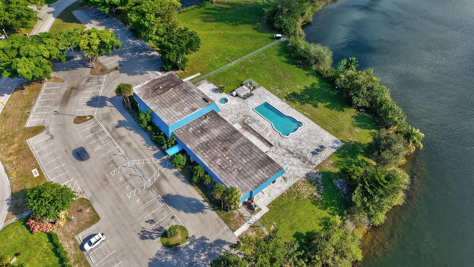 An aerial view shows a building with a pool, parking lot, and waterfront access — 4741 NW 13th Avenue, Deerfield Beach FL 33064, DEERFIELD BEACH, FL