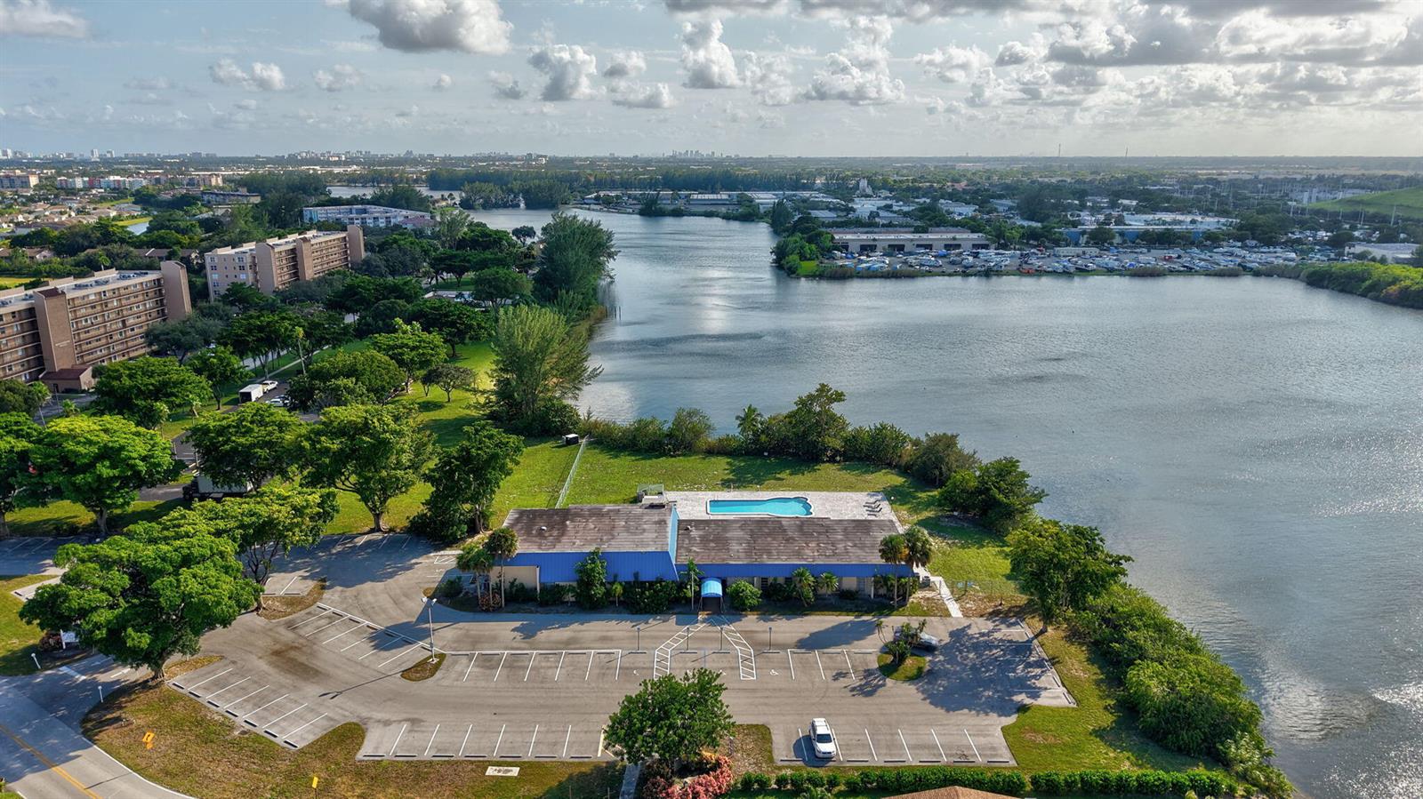 An aerial view shows a building with a blue roof, a pool, and a parking lot — 4741 NW 13th Avenue, Deerfield Beach FL 33064, DEERFIELD BEACH, FL