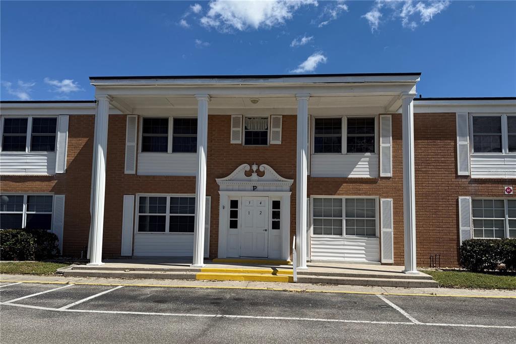 A two-story brick apartment building features a white columned porch and a central entrance — 4158 TAMIAMI TRAIL UNIT P1, PORT CHARLOTTE, FL