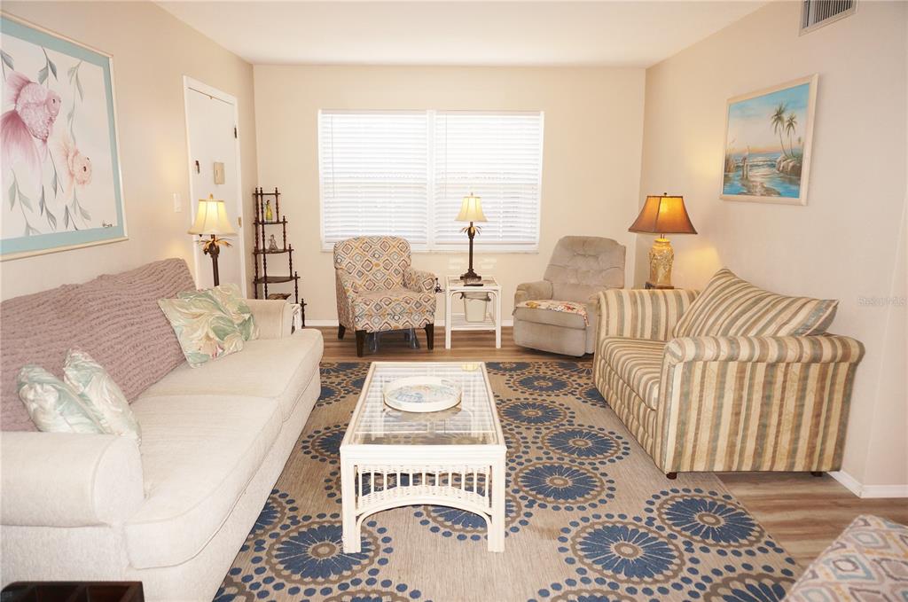 A living room features a sofa, patterned armchairs, a glass-topped coffee table, and a patterned rug — 4158 TAMIAMI TRAIL UNIT P1, PORT CHARLOTTE, FL