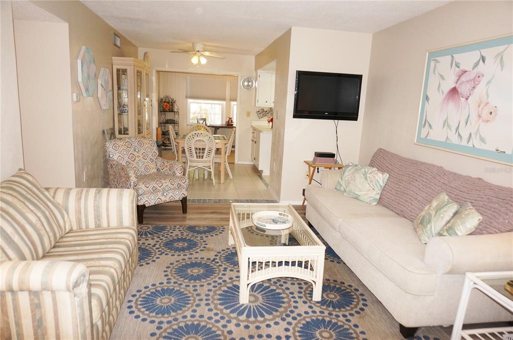 A living room with a patterned rug, two sofas, an armchair, and a dining area beyond — 4158 TAMIAMI TRAIL UNIT P1, PORT CHARLOTTE, FL