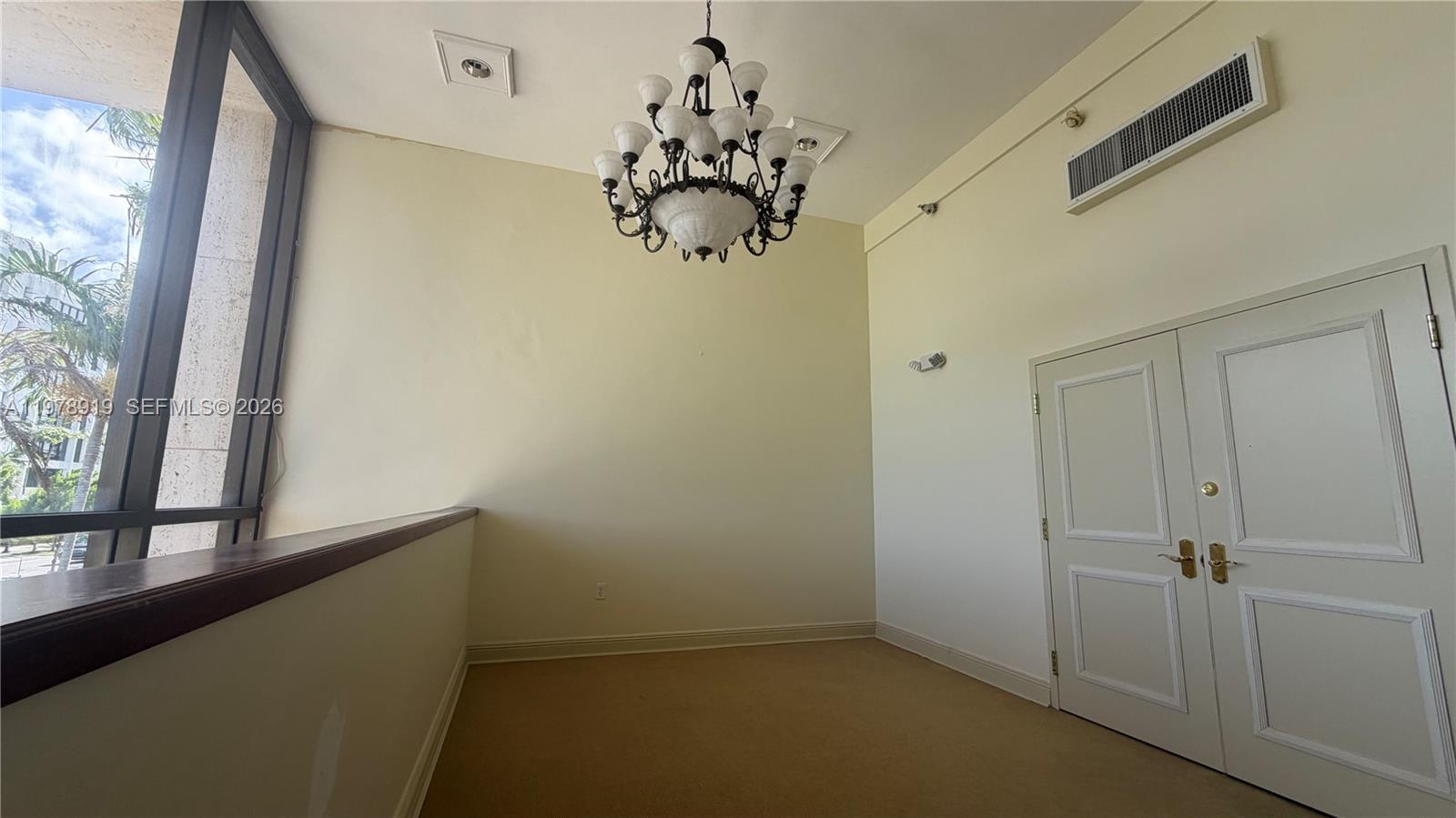 An interior room features a chandelier, beige carpeting, double doors, and a large window — 2435 Hollywood Blvd, Hollywood FL 33020, HOLLYWOOD, FL