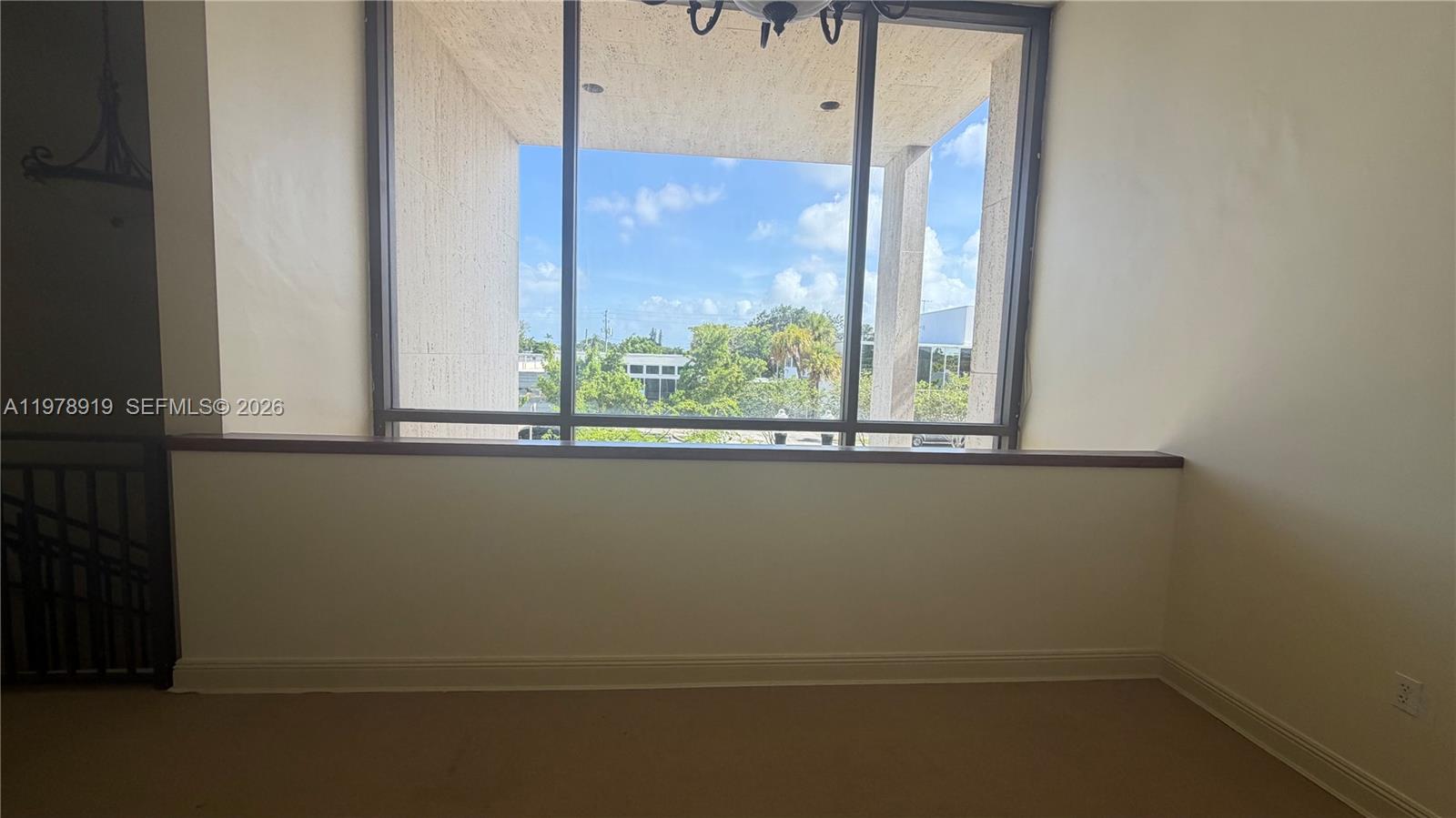 A room with beige carpet and a large window overlooking a balcony and trees — 2435 Hollywood Blvd, Hollywood FL 33020, HOLLYWOOD, FL