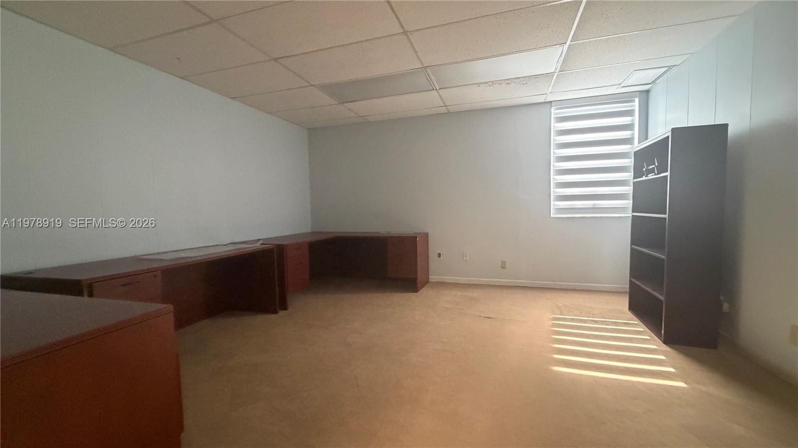 An office room features a built-in wooden desk, a tall bookshelf, and carpeted flooring — 2435 Hollywood Blvd, Hollywood FL 33020, HOLLYWOOD, FL