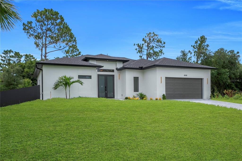 A modern, white single-story house with a dark roof and a two-car garage — 4048 CLEARFIELD STREET, NORTH PORT, FL