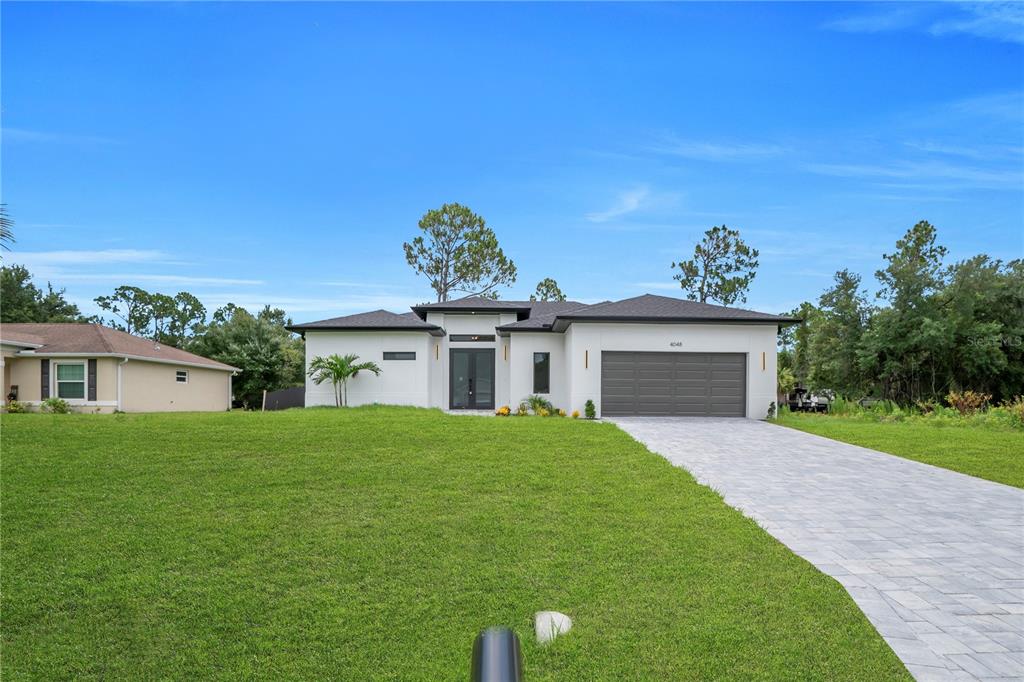 A modern single-story house features a gray garage door, white exterior, and paved driveway — 4048 CLEARFIELD STREET, NORTH PORT, FL
