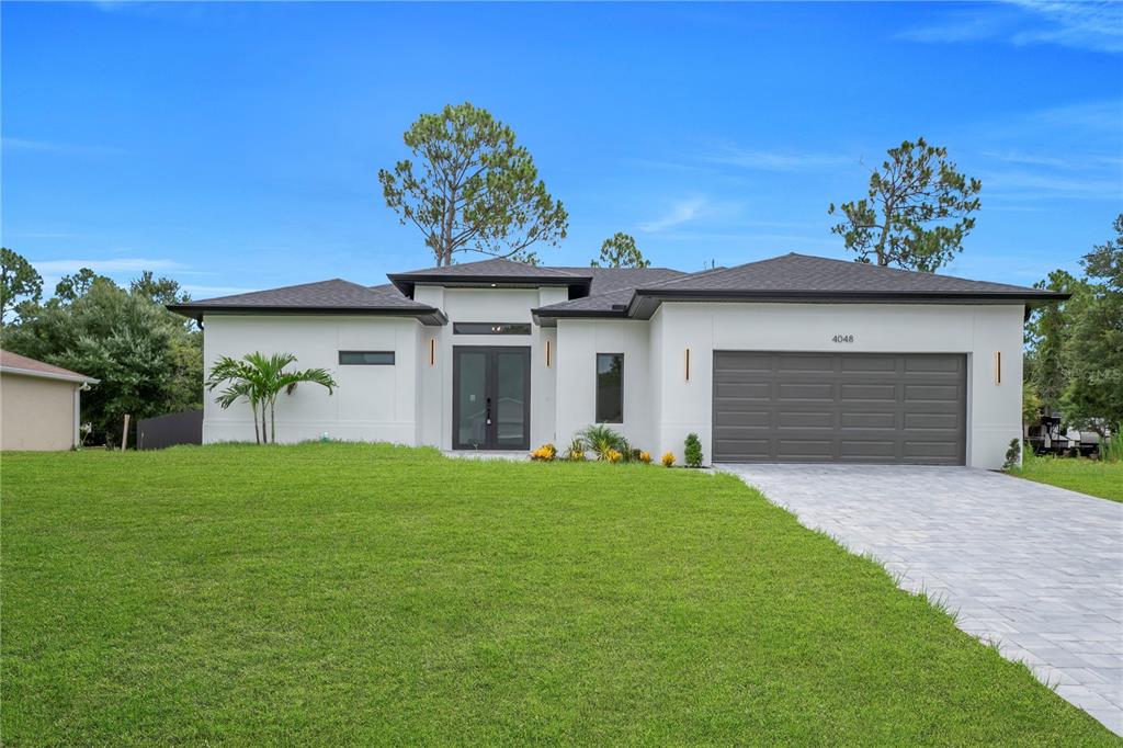 A modern single-story house with a paved driveway, white exterior, and a dark garage door — 4048 CLEARFIELD STREET, NORTH PORT, FL