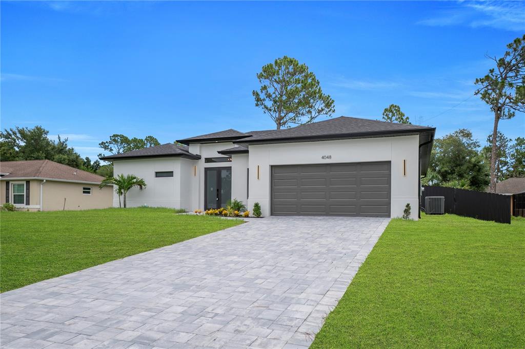 The exterior of a modern white house features a paved walkway and a gray garage — 4048 CLEARFIELD STREET, NORTH PORT, FL