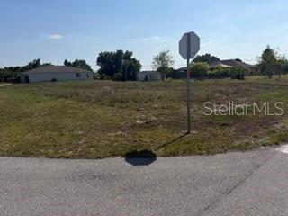A vacant, grassy residential lot is viewed from a street corner with a stop sign — 2993 SEAFARER DRIVE, PUNTA GORDA, FL