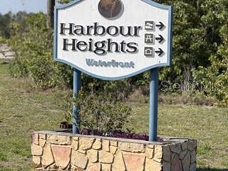 A stone-based sign for Harbour Heights Waterfront stands in a grassy area with trees behind — 2993 SEAFARER DRIVE, PUNTA GORDA, FL