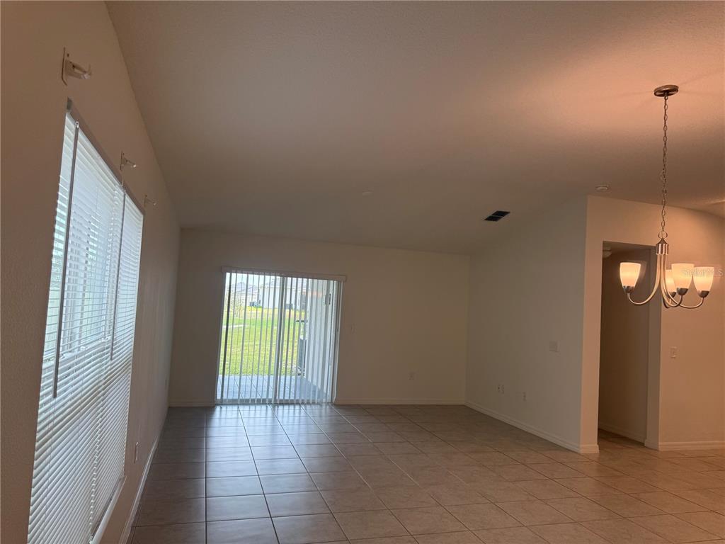 An open-concept living area features light tile flooring, white walls, and a sliding glass door — 711 SCRUB OAK HAMMOCK ROAD, DAVENPORT, FL