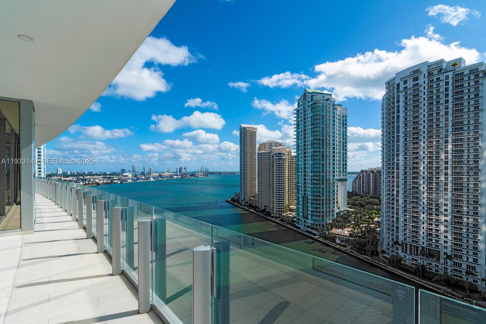 A high-rise balcony with a glass railing overlooks a bay and city skyline — 300 Biscayne Blvd Way # 1901, Miami FL 33131, MIAMI, FL