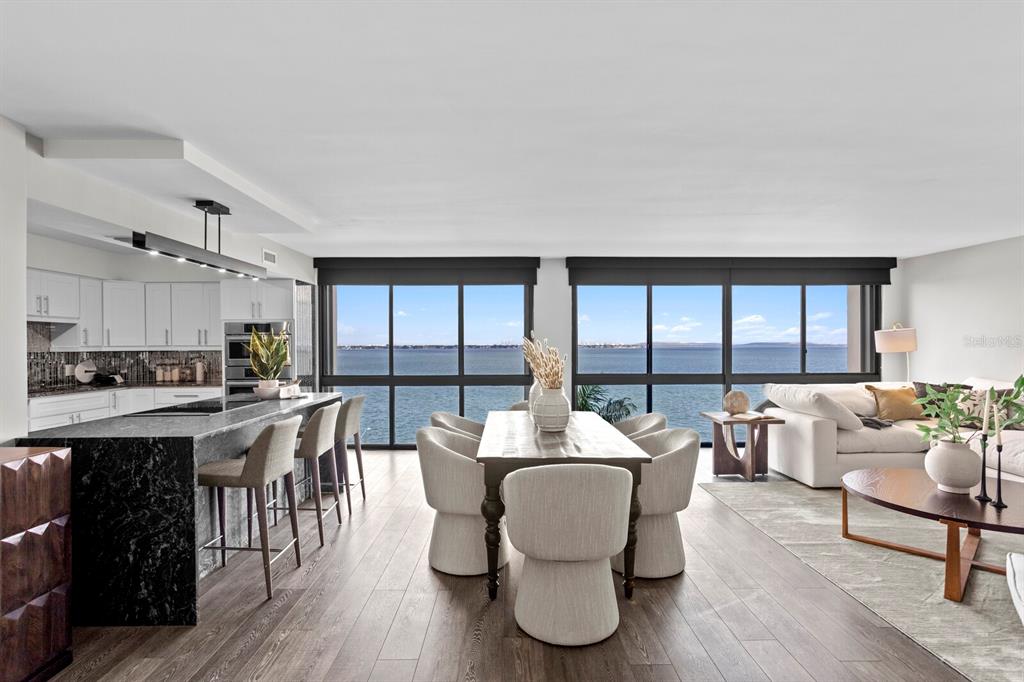 An open-concept living and dining area features a kitchen island, floor-to-ceiling windows, and water views — 3301 BAYSHORE BOULEVARD UNIT 806C, TAMPA, FL