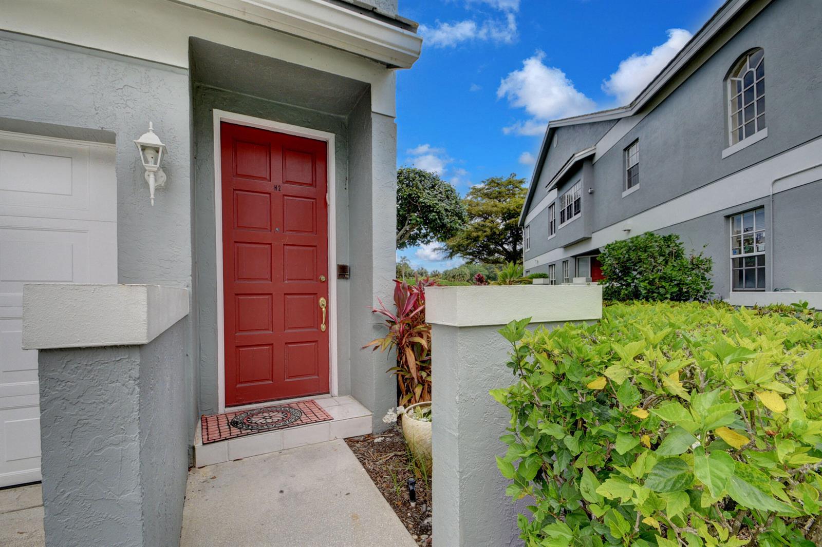 A red front door is set in a gray stucco building with a concrete walkway — 10220 Andover Coach Circle # H2, Lake Worth FL 33449, LAKE WORTH, FL