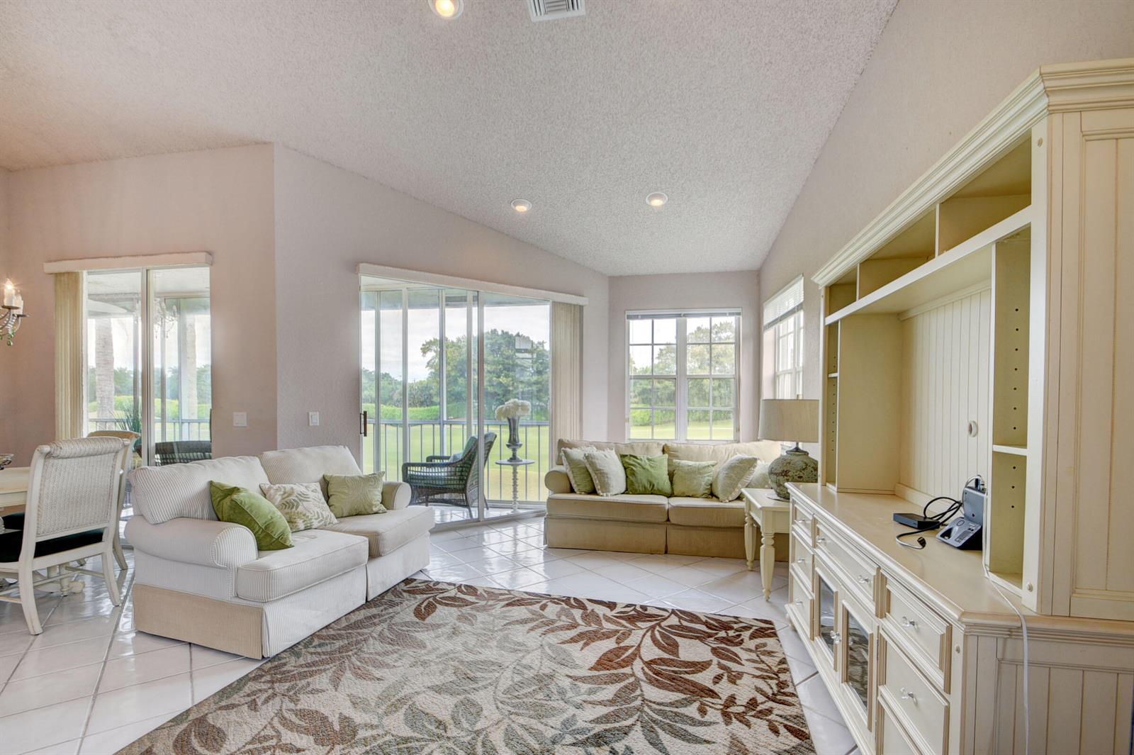 A living room features light-colored furniture, a patterned area rug, tile floors, and large windows — 10220 Andover Coach Circle # H2, Lake Worth FL 33449, LAKE WORTH, FL