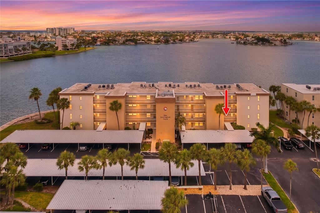 An aerial view of a multi-story apartment building with a red arrow pointing to a balcony — 7920 SUN ISLAND DRIVE S UNIT 202, SOUTH PASADENA, FL
