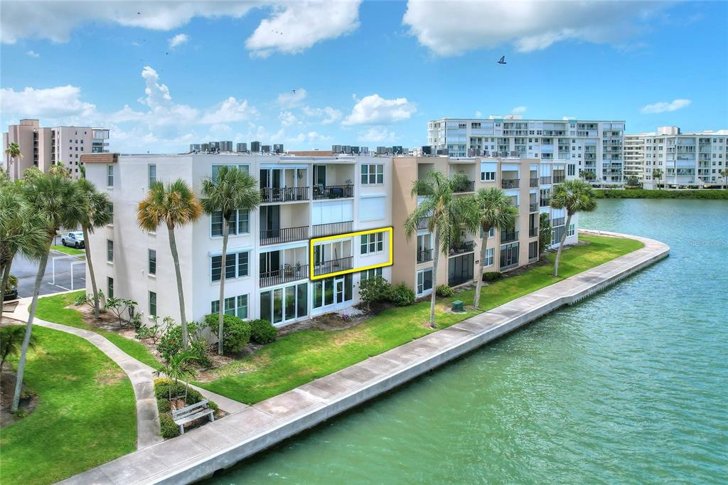 An exterior view of a multi-story waterfront apartment building with a highlighted balcony unit — 7920 SUN ISLAND DRIVE S UNIT 202, SOUTH PASADENA, FL