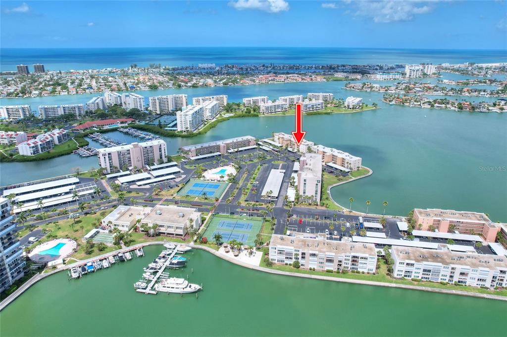 An aerial view shows a waterfront residential complex with tennis courts, a marina, and pools — 7920 SUN ISLAND DRIVE S UNIT 202, SOUTH PASADENA, FL