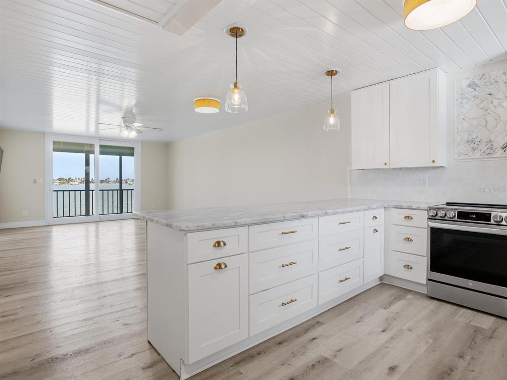 A kitchen with white cabinets, marble countertops, and a view of the water through sliding doors — 7920 SUN ISLAND DRIVE S UNIT 202, SOUTH PASADENA, FL