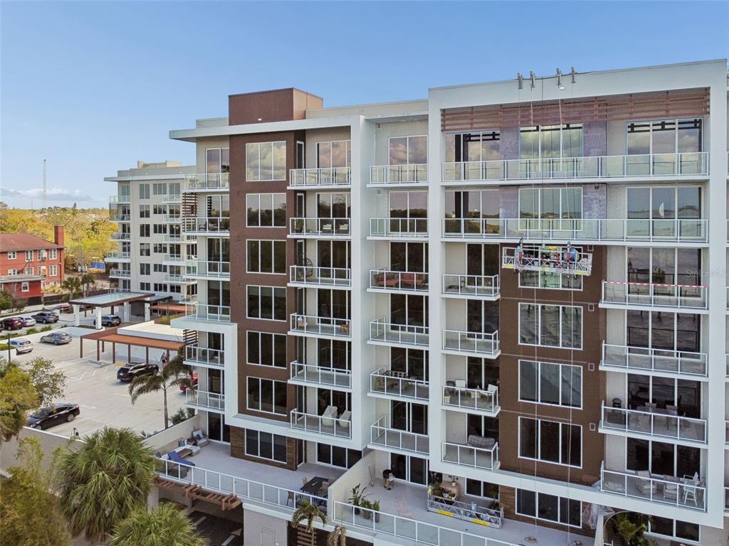 An exterior view of a modern multi-story apartment building with balconies and a parking lot — 920 N OSCEOLA AVENUE UNIT 604, CLEARWATER, FL