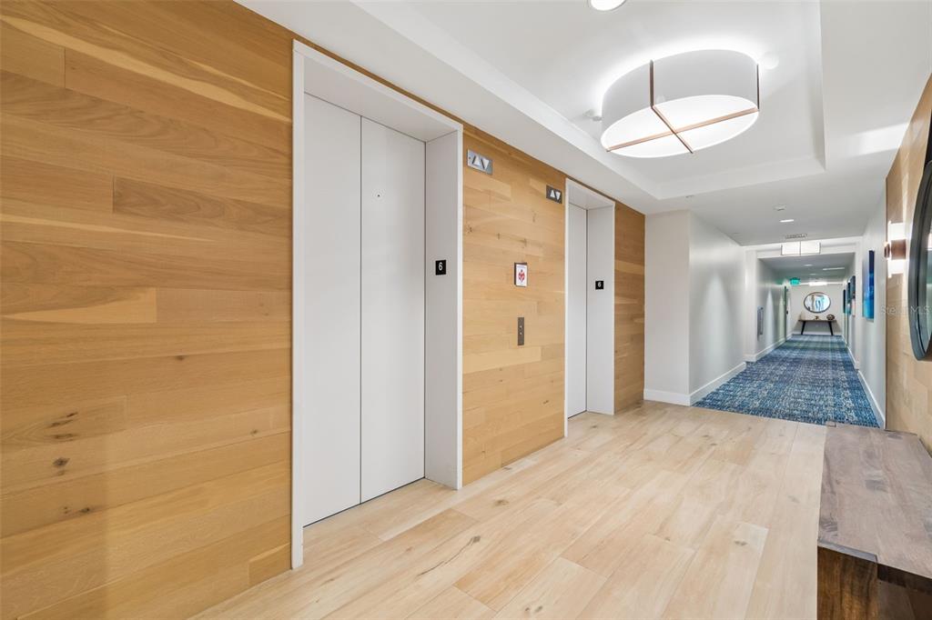 A hallway with wood-paneled walls, light wood flooring, and two white elevator doors — 920 N OSCEOLA AVENUE UNIT 604, CLEARWATER, FL