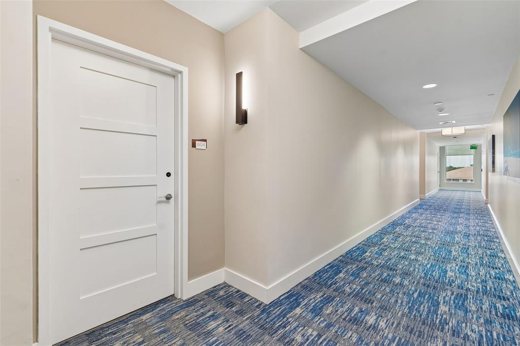 A white door with a room number sign sits in a hallway with blue carpeting — 920 N OSCEOLA AVENUE UNIT 604, CLEARWATER, FL