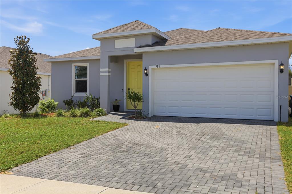 A single-story house with a gray exterior, yellow front door, and a paved driveway — 788 RICHMOND ESTATE AVENUE, HAINES CITY, FL