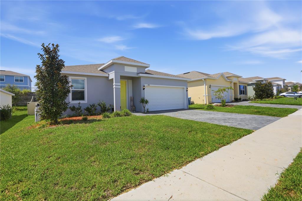 A single-story house with a gray exterior, a white garage door, and a yellow front door — 788 RICHMOND ESTATE AVENUE, HAINES CITY, FL