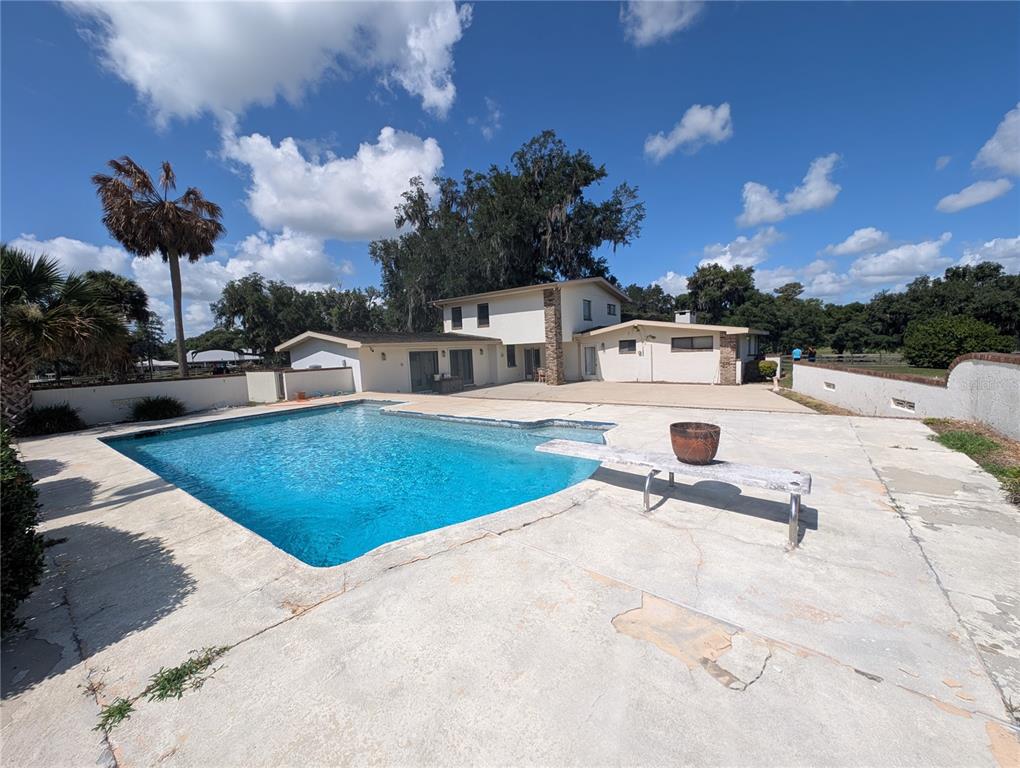 A backyard features a rectangular swimming pool with a diving board and a two-story house — 1750 SE 80TH STREET, OCALA, FL