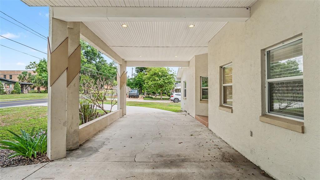 A concrete carport with a white ceiling and two support pillars attached to a house — 926 HOLLINGSWORTH ROAD, LAKELAND, FL