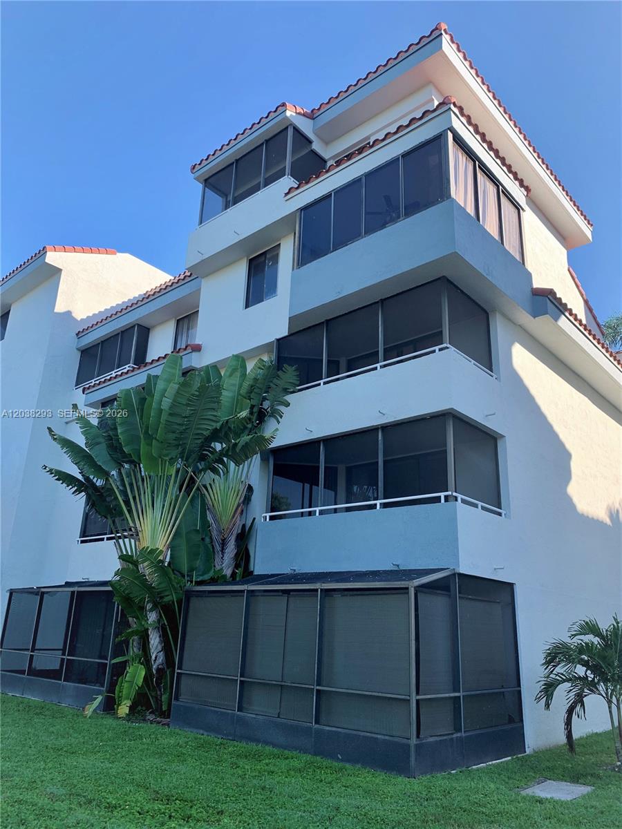 A multi-story residential building features screened-in balconies and a large tropical plant in front — 8255 SW 152nd Ave # 101, Miami FL 33193, MIAMI, FL