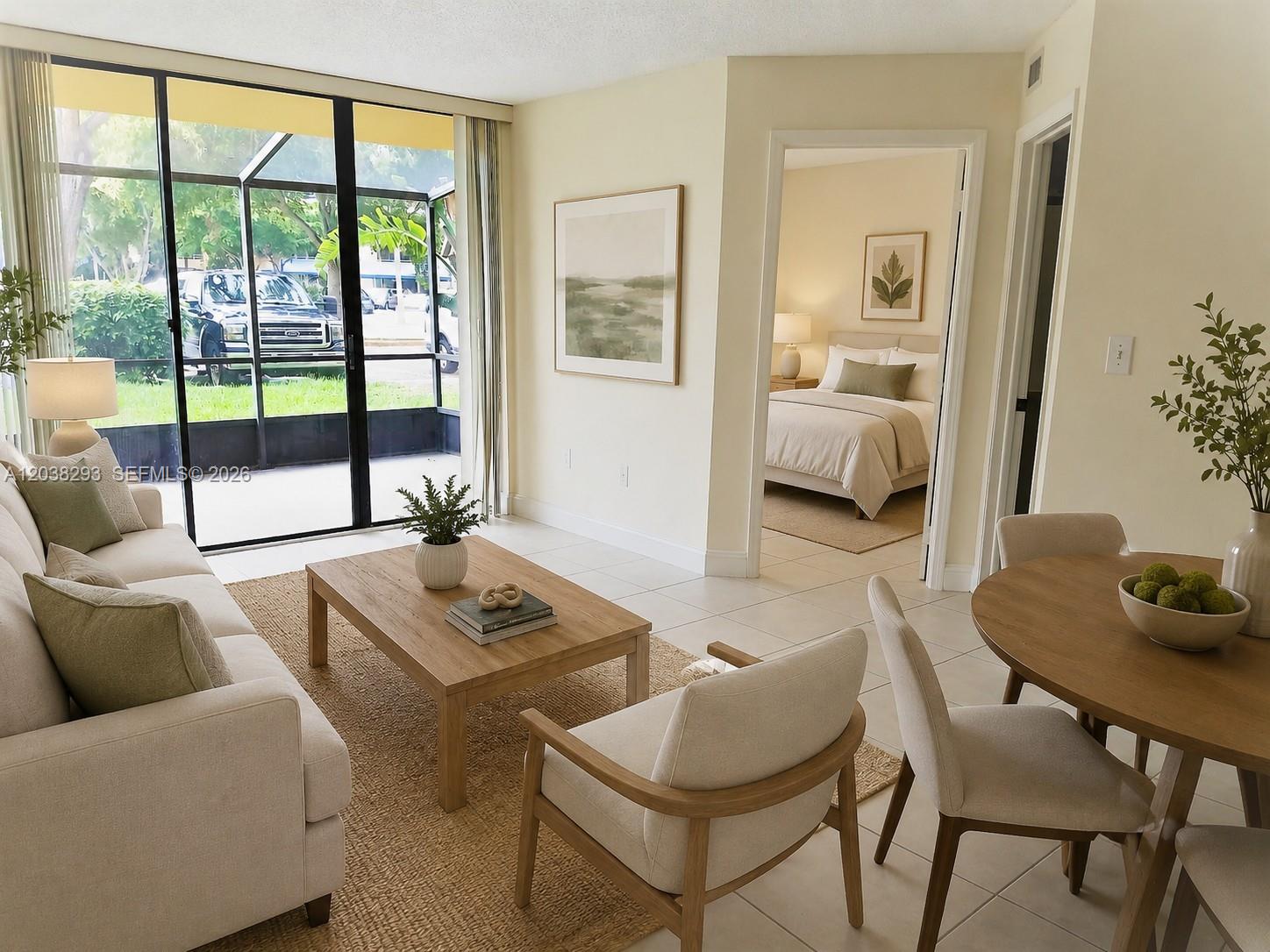 A living room with light tile floors, a neutral sofa, and a view of a patio — 8255 SW 152nd Ave # 101, Miami FL 33193, MIAMI, FL