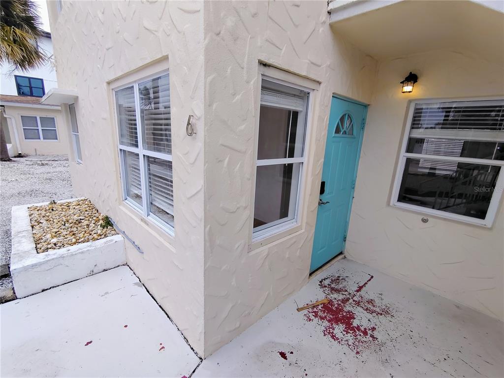 An exterior view of a building entrance with a blue door and red staining — 115 145TH AVENUE E UNIT 6, MADEIRA BEACH, FL