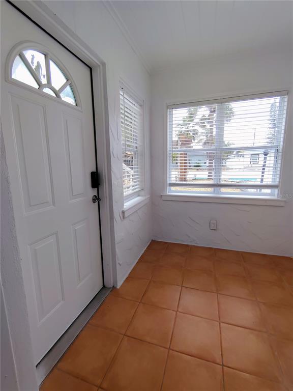 An entryway with a white door, tiled floor, and a window with horizontal blinds — 115 145TH AVENUE E UNIT 6, MADEIRA BEACH, FL