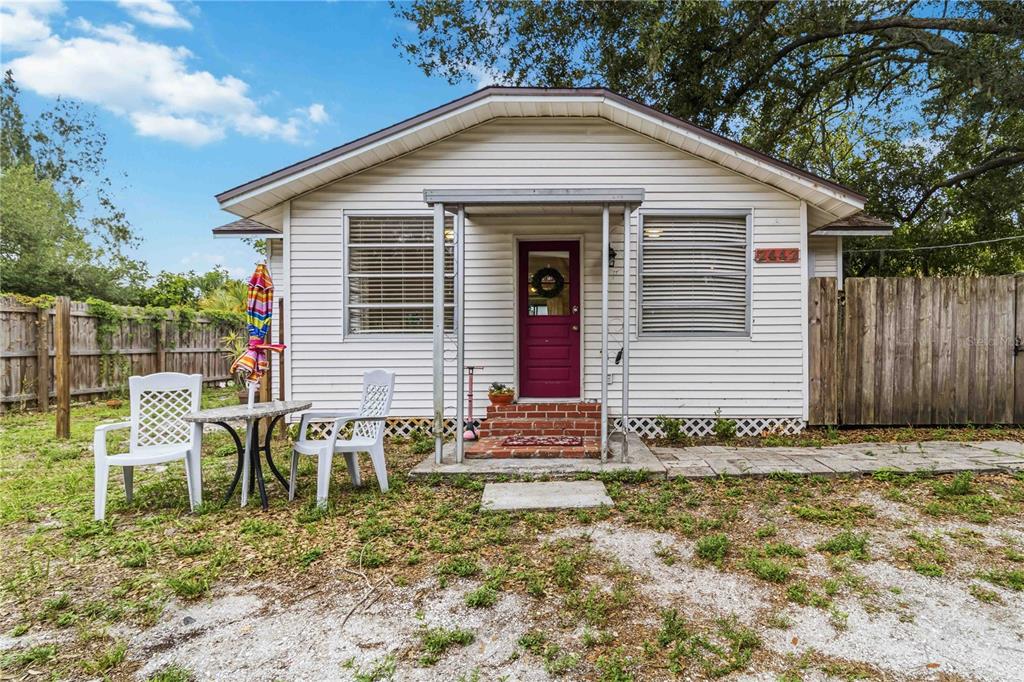 A small, white, single-story house with a red front door and a gravel yard — 2442 NOVUS STREET, SARASOTA, FL