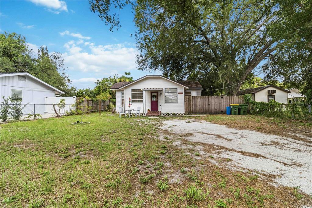 A white single-story house with a red front door sits behind a large dirt driveway — 2442 NOVUS STREET, SARASOTA, FL