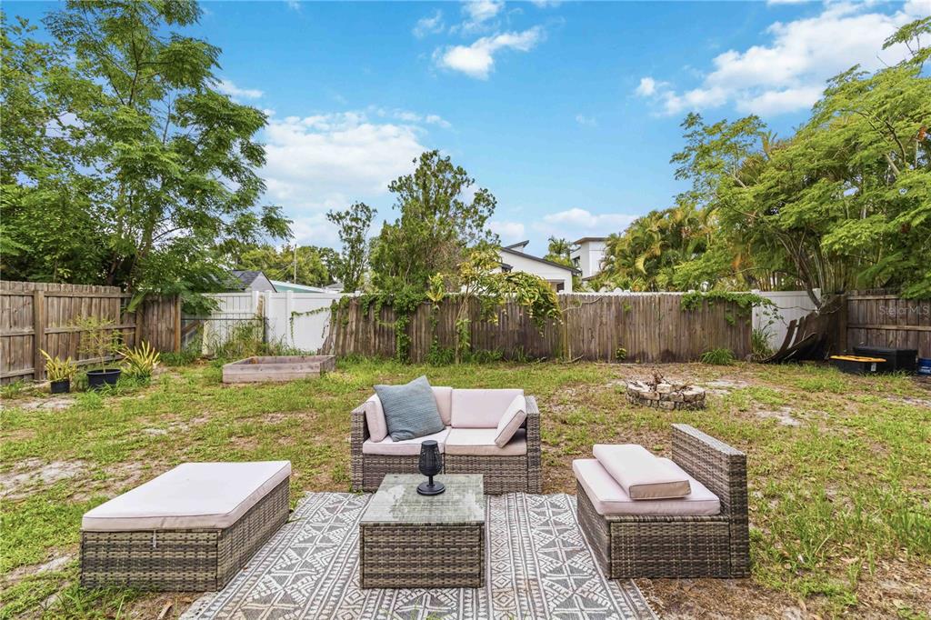 A backyard features a patio set on a rug, a fire pit, and wooden fencing — 2442 NOVUS STREET, SARASOTA, FL
