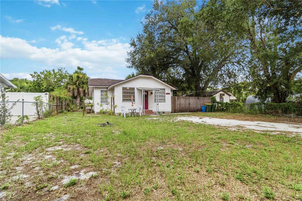 A single-story white house with a red door sits on a grassy lot with trees — 2442 NOVUS STREET, SARASOTA, FL