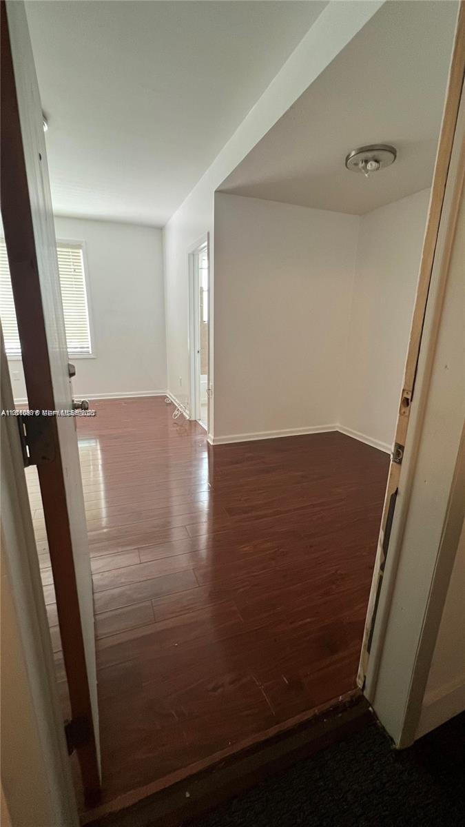 An interior view shows a room with dark wood-look flooring and white walls — 1502 Jefferson Ave # 102, Miami Beach FL 33139, MIAMI BEACH, FL