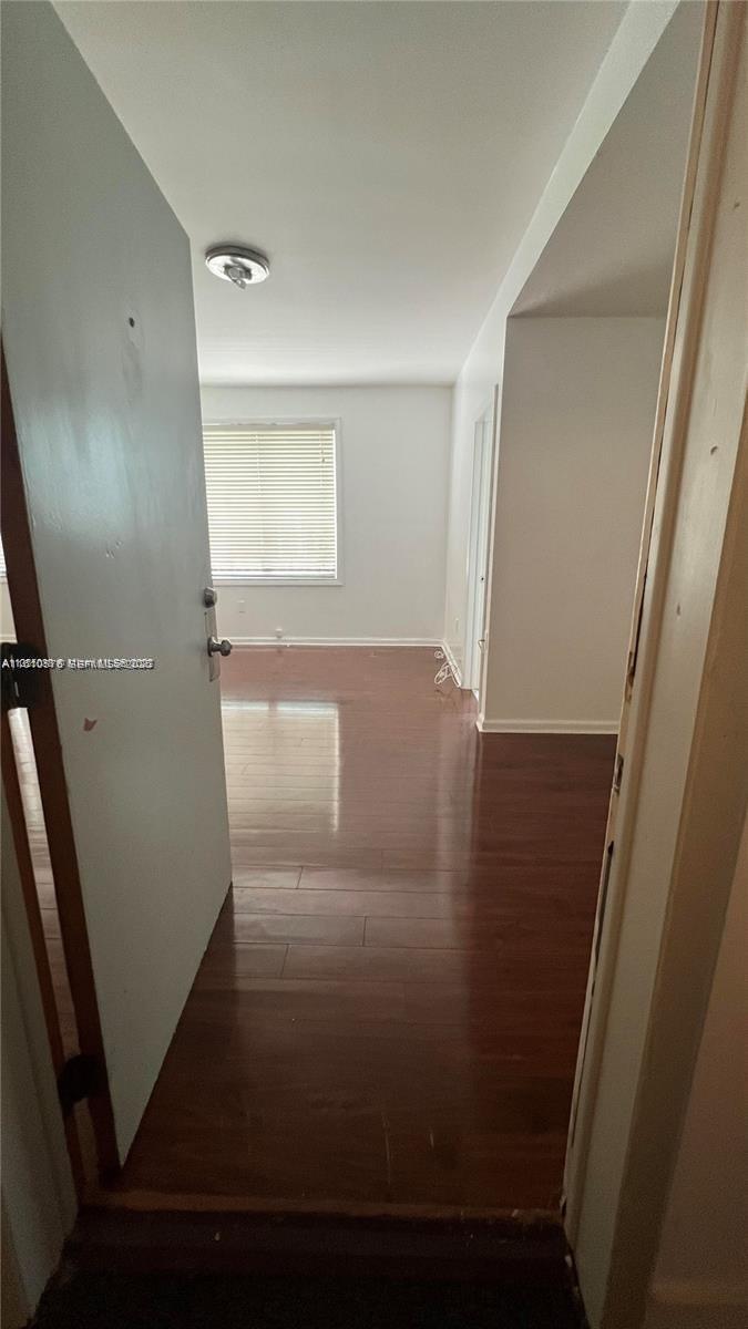 An interior view shows a room with dark wood-look flooring and a white window — 1502 Jefferson Ave # 102, Miami Beach FL 33139, MIAMI BEACH, FL