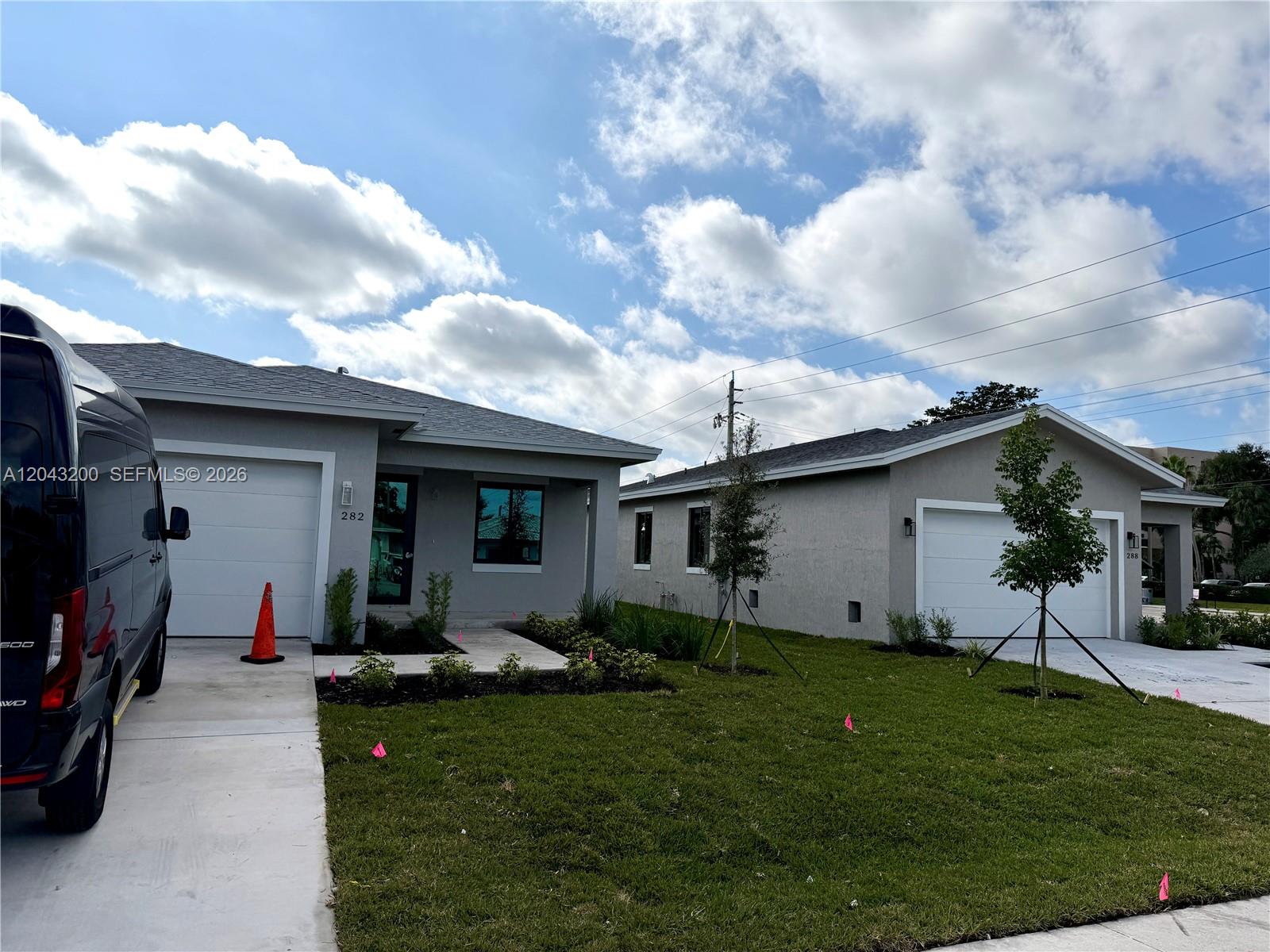 Two modern, single-story gray houses with white garage doors stand side-by-side under a cloudy sky — 282 SW 2nd Ct, Deerfield Beach FL 33441, DEERFIELD BEACH, FL