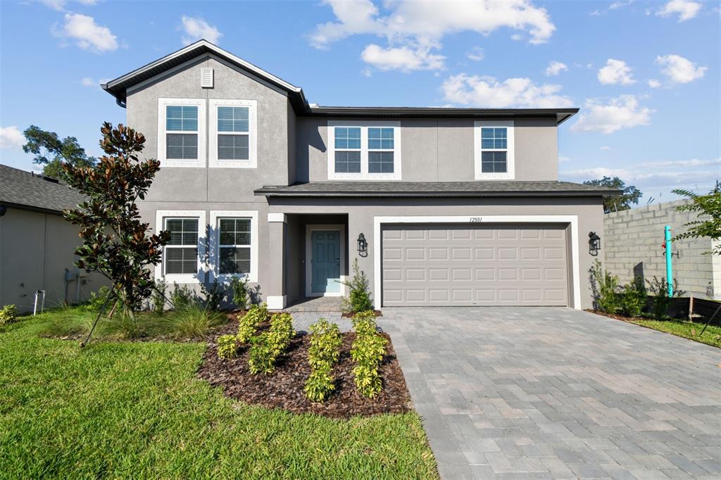 A two-story gray house features a paved driveway, a two-car garage, and a front garden — 12801 CASTLE OAKS DRIVE, HUDSON, FL