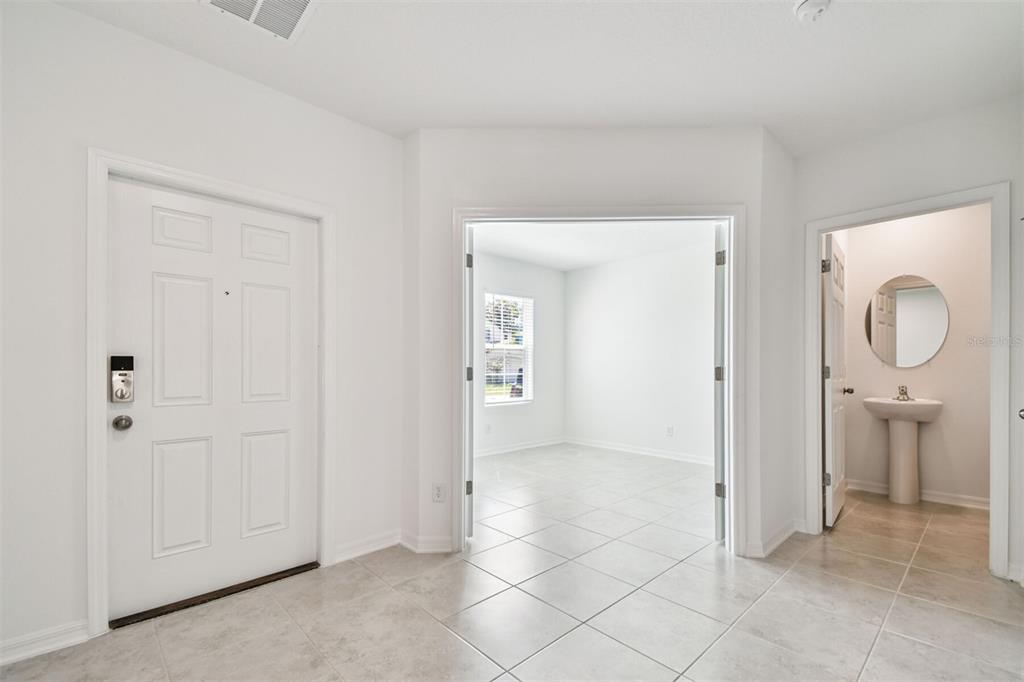 An entryway with tile flooring leads to a room with French doors and a powder room — 12801 CASTLE OAKS DRIVE, HUDSON, FL