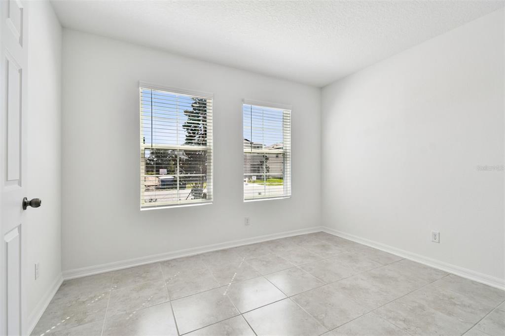 An empty room with white walls, light-colored tile flooring, and two windows with blinds — 12801 CASTLE OAKS DRIVE, HUDSON, FL