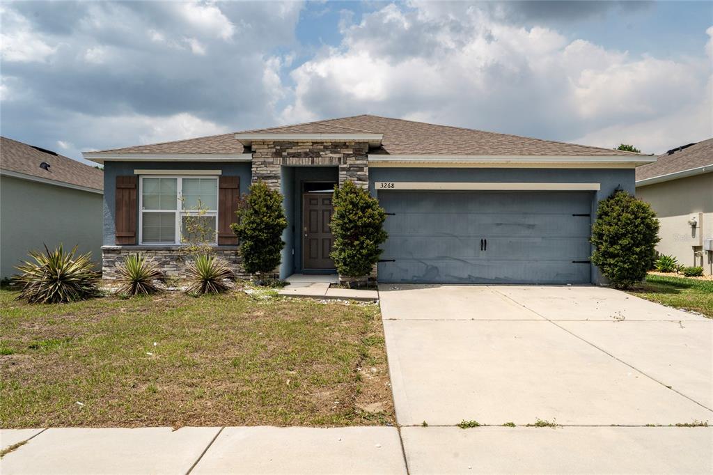 A single-story house with a blue exterior, stone accents, and a two-car garage — 3268 COUNTRY WALK CLUB CIRCLE, WINTER HAVEN, FL