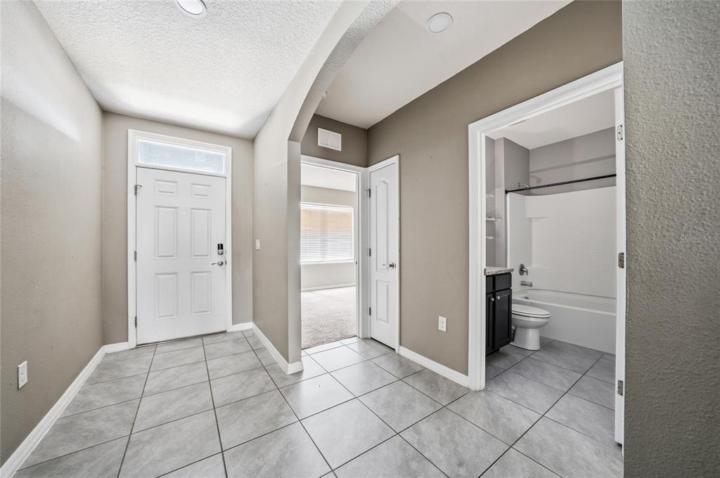 A tiled entryway leads to a bathroom on the right and a carpeted room ahead — 3268 COUNTRY WALK CLUB CIRCLE, WINTER HAVEN, FL