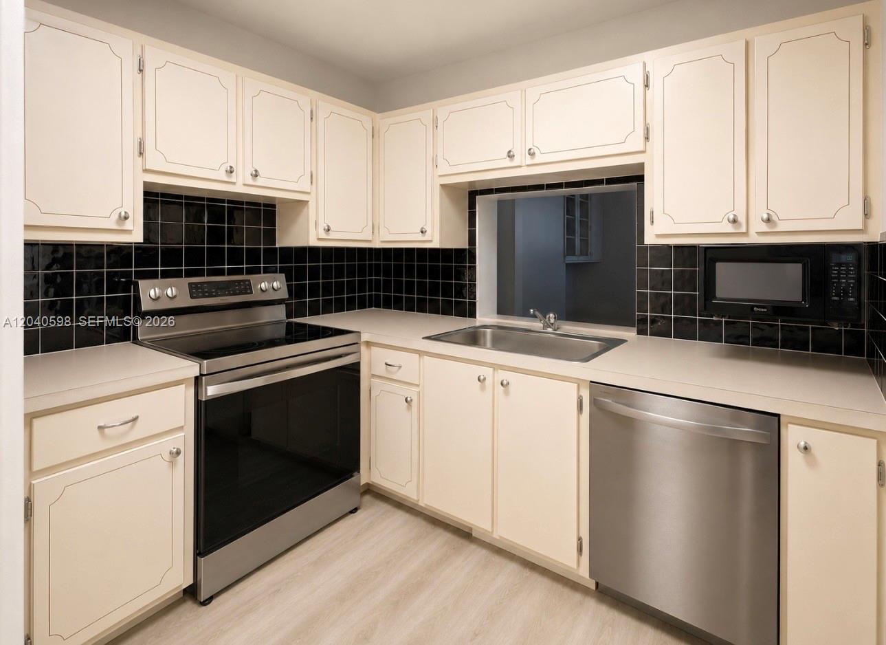 A kitchen features off-white cabinets, black tile backsplashes, and stainless steel appliances — 1893 S Ocean Dr # 601, Hallandale Beach FL 33009, HALLANDALE BEACH, FL