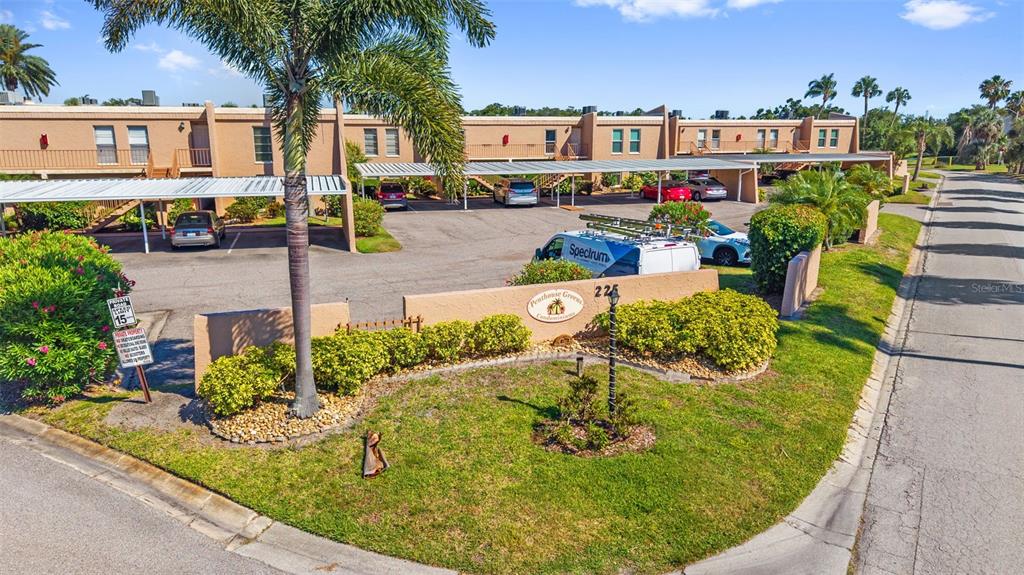 An exterior view of a multi-story apartment complex with covered parking and a landscaped entrance — 225 COUNTRY CLUB DRIVE UNIT B221, LARGO, FL