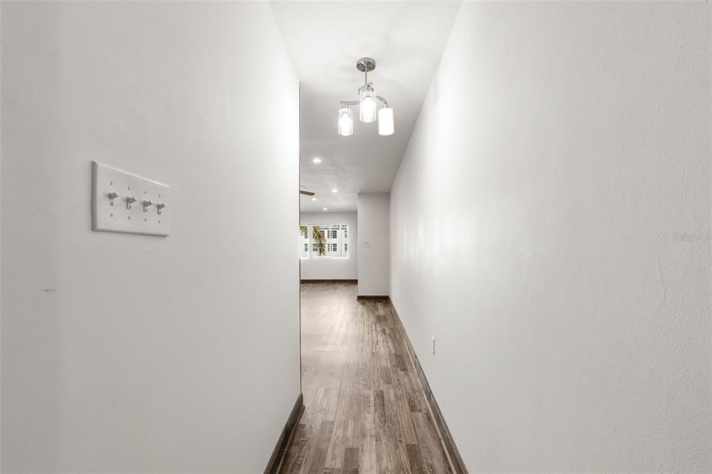 A narrow hallway with light-colored walls, wood-look flooring, and a three-light ceiling fixture — 225 COUNTRY CLUB DRIVE UNIT B221, LARGO, FL